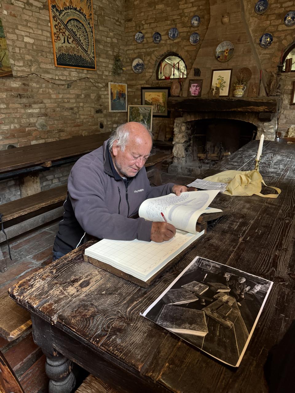 on voit Danilo entrain de consulter un annuaire très ancien sur une table en bois massif dans un décor très vieillot