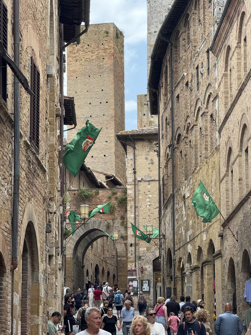 une ruelle avec plein de gens et des bâtiments fortifiés