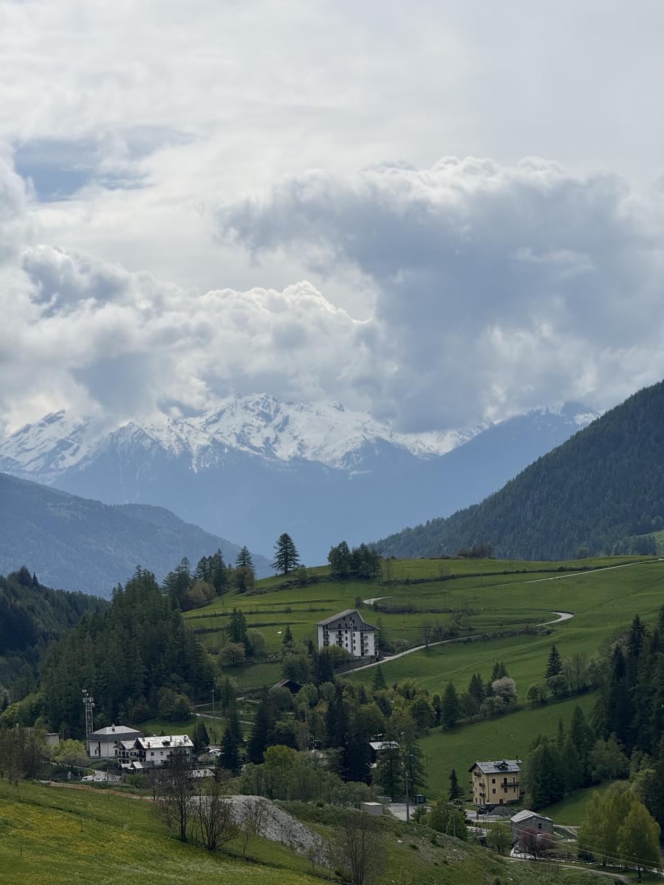 une maison sur de l'herbe verte au premier plan entre deux montagnes au second