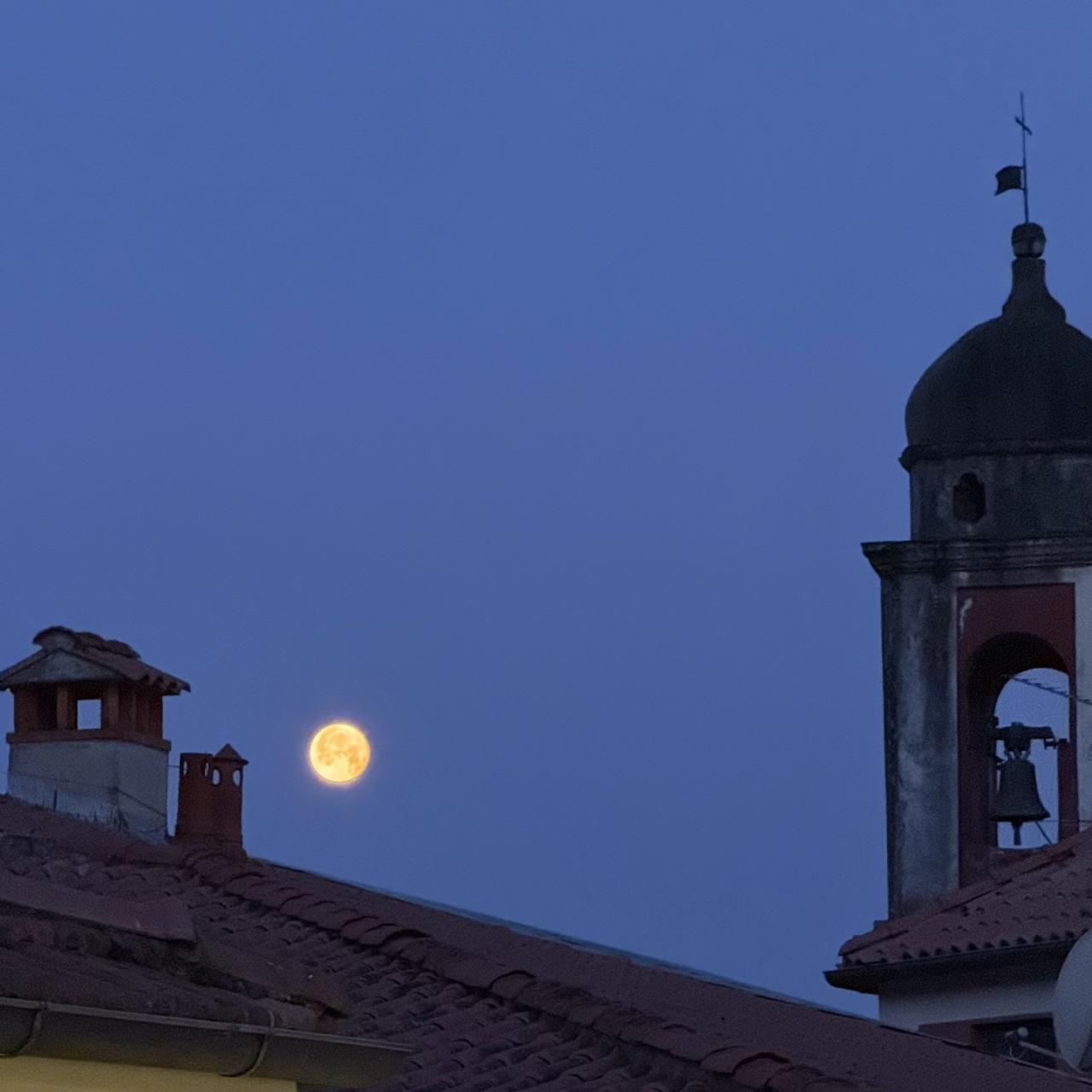 de nuit on voit la lune rousse et un clocher