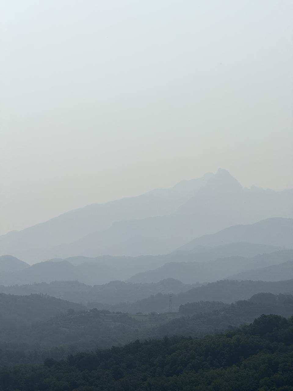 plusieurs niveau de montagnes les unes derrière les autres couleur pastel a cause du brouillard (ou de la pollution)